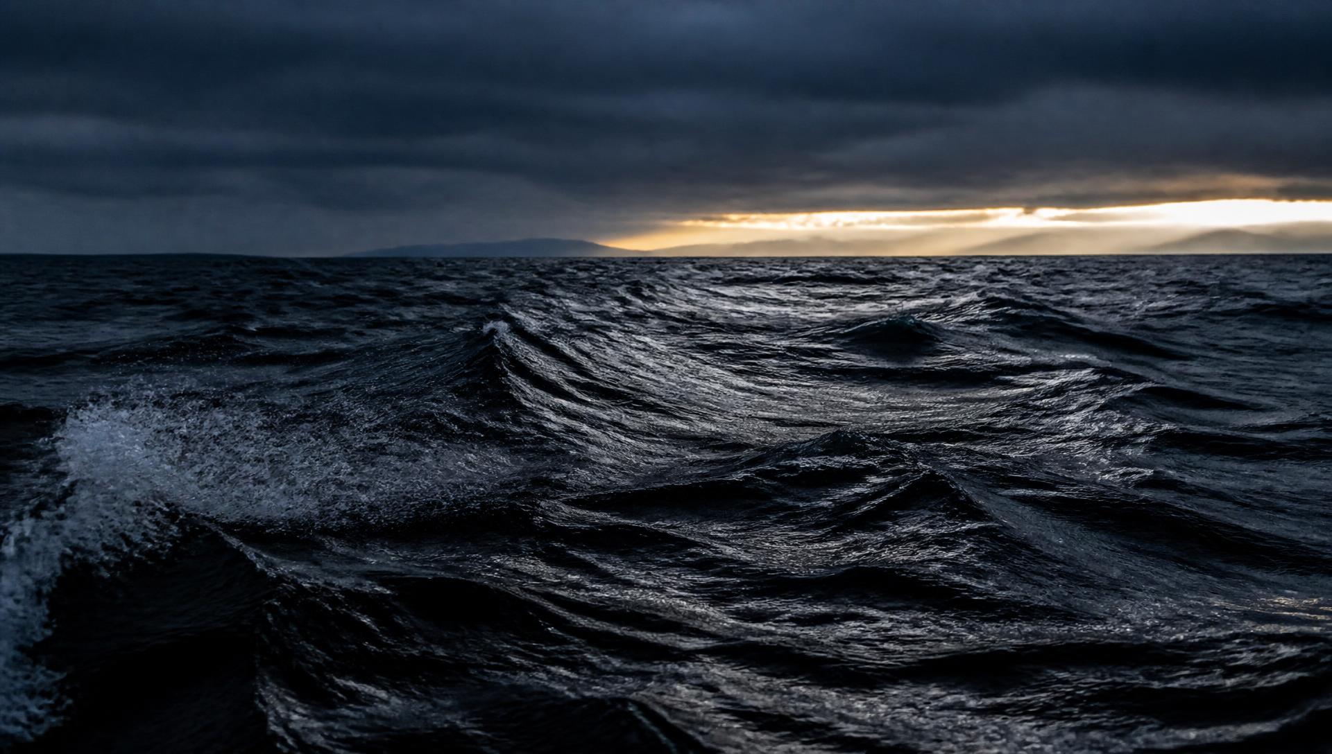Dark wind-scoured open water at first light beneath a slate storm band